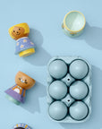 Wooden kokeshi doll parts and a carton of blue eggs on a light blue background.