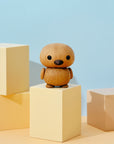 A small wooden bird figurine on pastel-colored blocks against a light blue background.