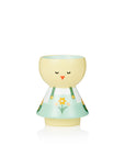 A pastel-colored kokeshi doll with a yellow head, closed eyes, and a floral dress.