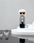 Kokeshi doll with sunglasses on a white platform, with reflective spheres nearby.