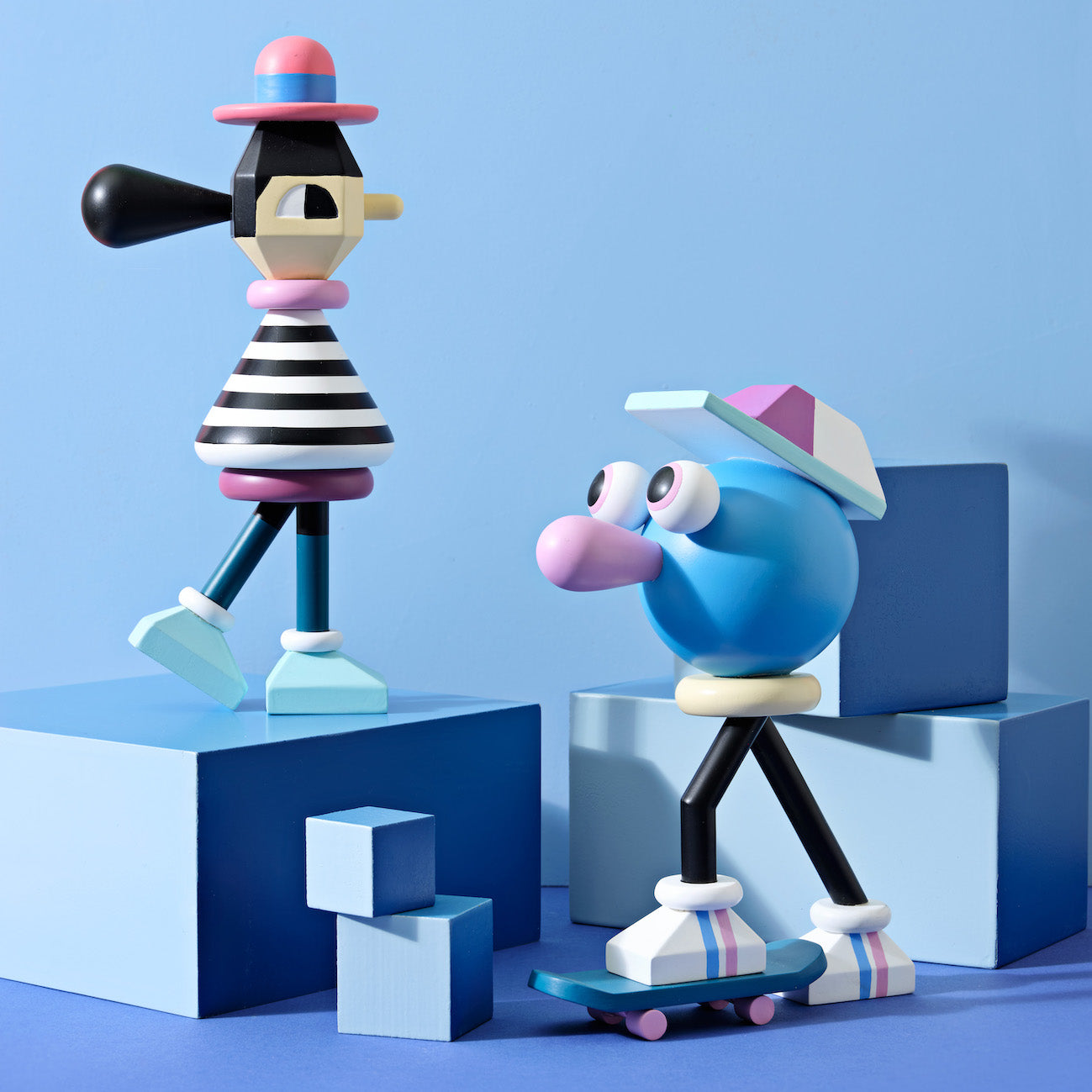 Colorful, abstract wooden figures with hats and striped patterns on blue geometric blocks.