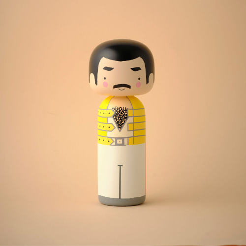 A kokeshi doll with a yellow jacket and black hair on a beige background.