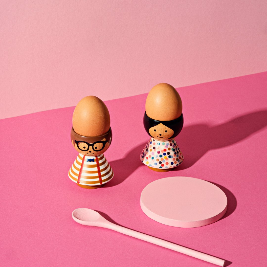 Two egg holders on a table in a pink photo shoot environment