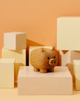 Eine hölzerne Schweinefigur auf einem Display aus beige- und cremefarbenen geometrischen Blöcken.