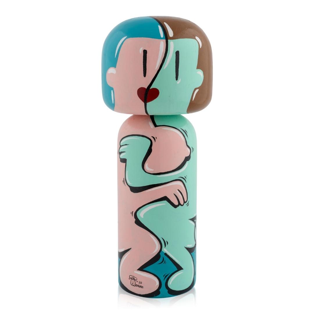 Farbenfrohe Kokeshi-Puppe mit abstraktem Muster aus ineinander verschlungenen Figuren in Pastelltönen.