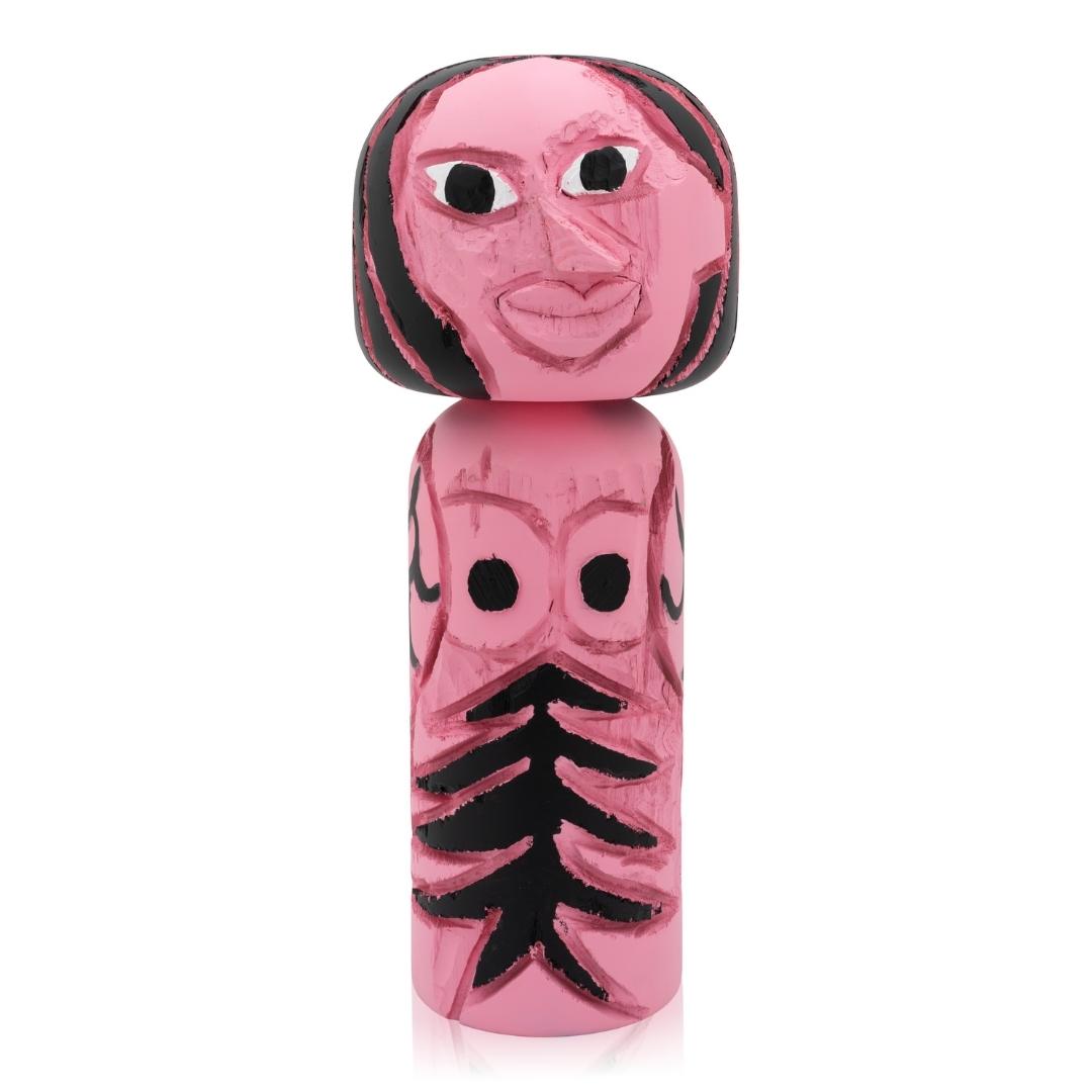 Rosa Kokeshi-Puppe mit abstrakten schwarzen Gesichtszügen und Baummuster auf dem Körper.