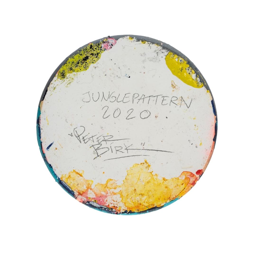 Ein runder, farbenfroher Sockel mit der handschriftlichen Aufschrift "JUNGLEPATTERN 2020" und "PEAP BIRK".