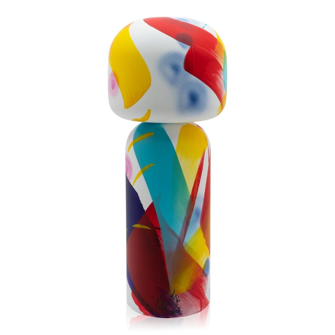 Bunte Kokeshi-Puppe mit abstrakten Pinselstrichen in Rot, Gelb, Blau und Weiß.