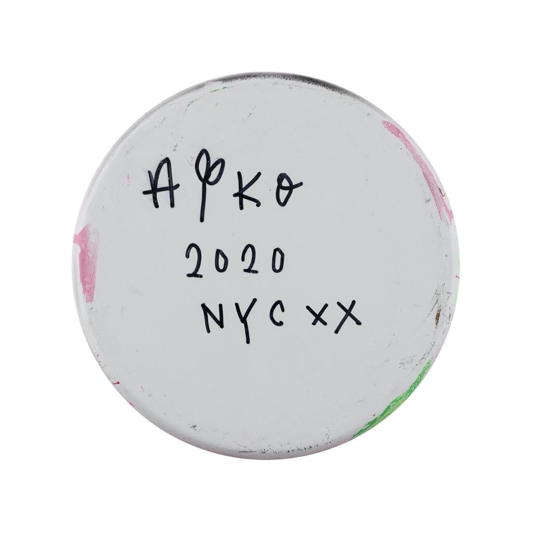 Unterseite eines runden Objekts mit handschriftlichem Text: "Aiko 2020 NYC XX" und bunten Flecken.