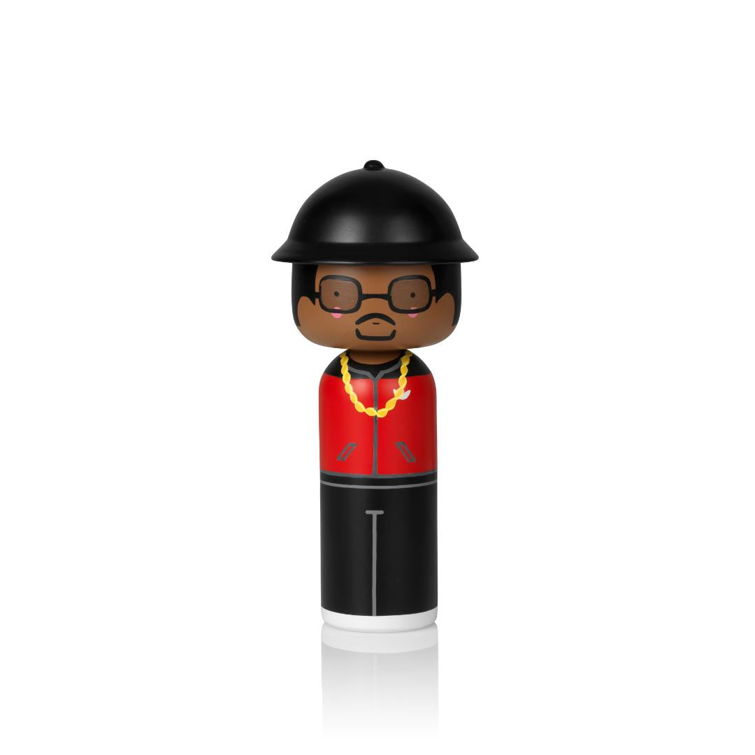 Eine Kokeshi-Puppe mit schwarzem Hut, Brille, roter Jacke und goldener Kette auf weißem Hintergrund.