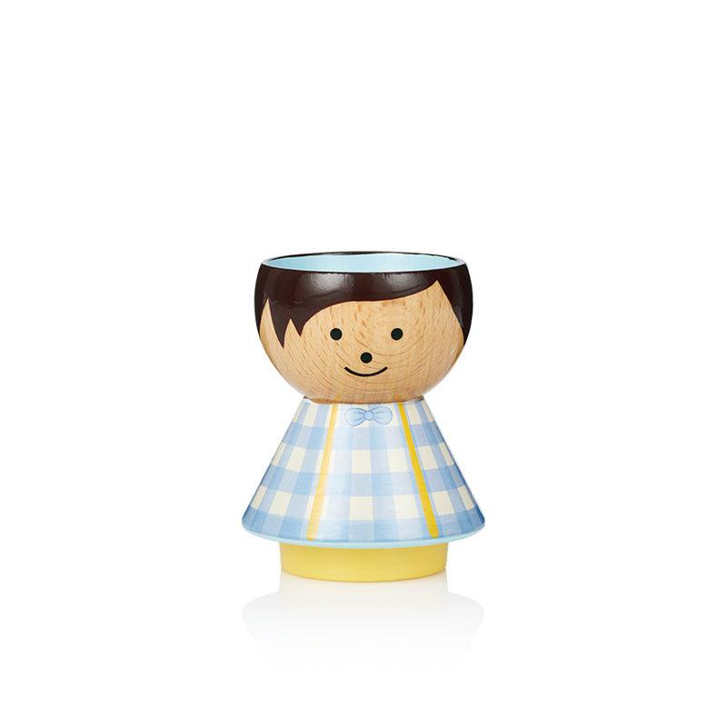 Eine hölzerne Kokeshi-Puppe mit einem blau-karierten Kleid und einem lächelnden Gesicht.