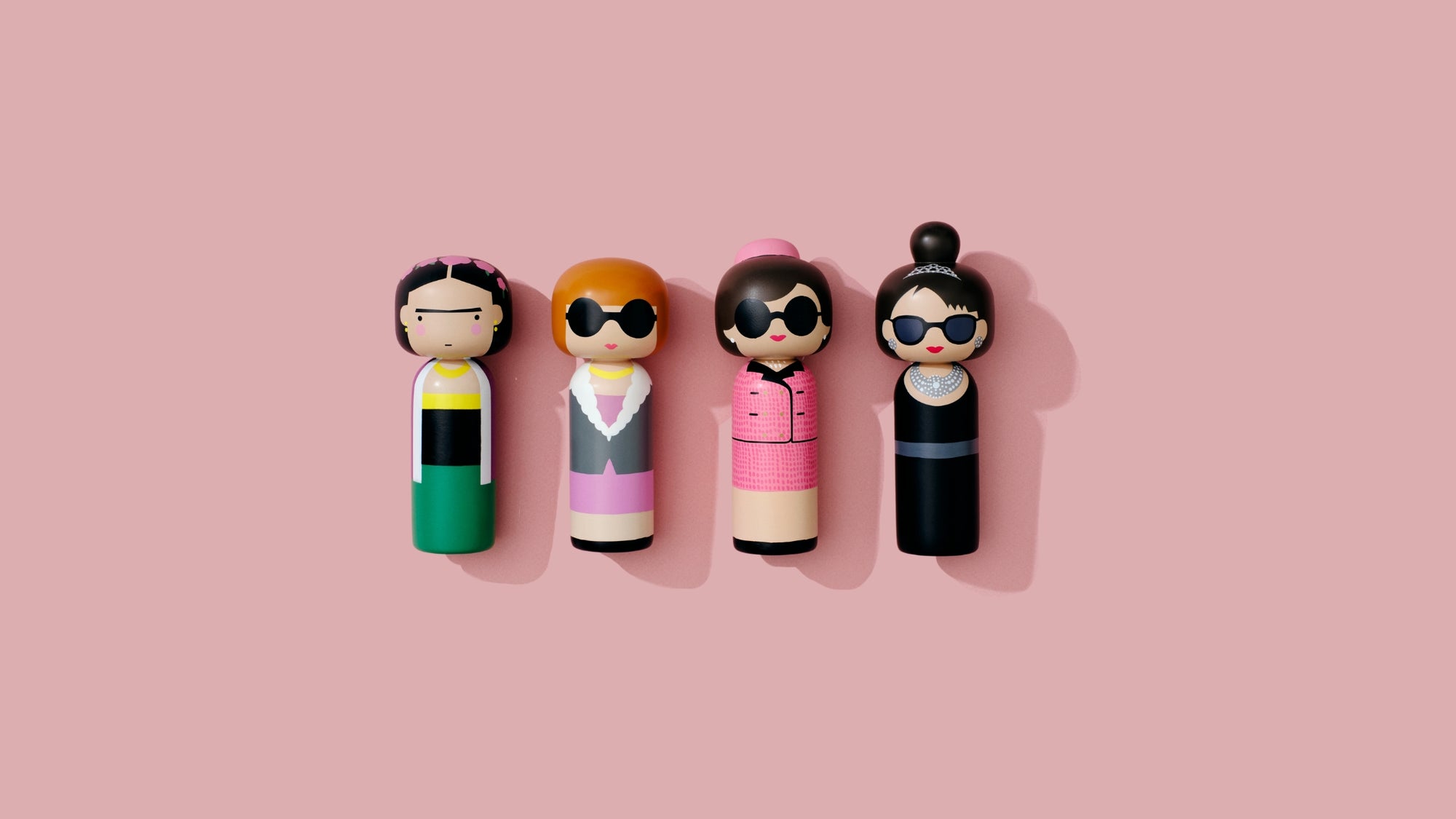 Vier stilvolle Kokeshi-Puppen mit Sonnenbrillen auf einem rosa Hintergrund.