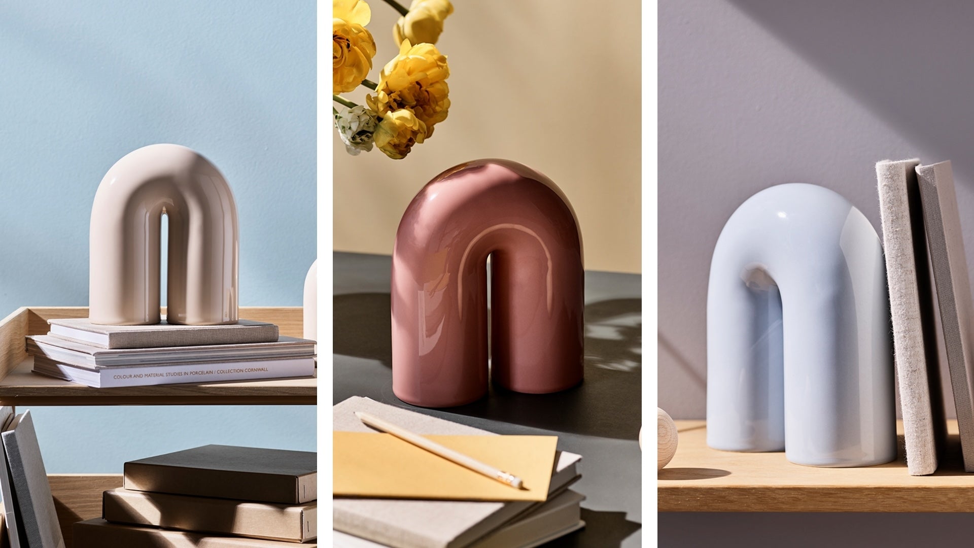 Drei bogenförmige Keramikvasen in Pastellfarben auf Regalen mit Büchern und Blumen.