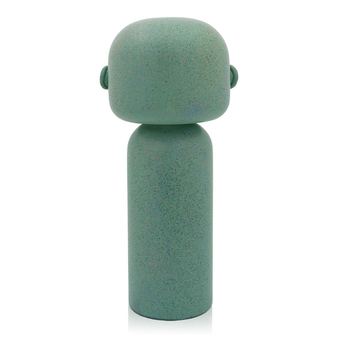 Grüne Kokeshi-Puppe mit glattem, abgerundetem Kopf und zylindrischem Körper, von hinten gesehen.