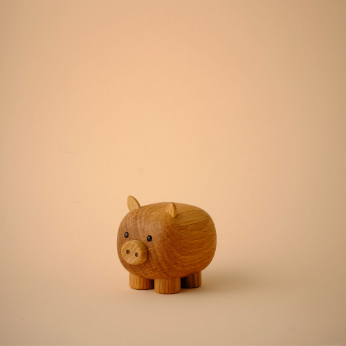 Petite figurine de cochon en bois au design simple sur fond beige.