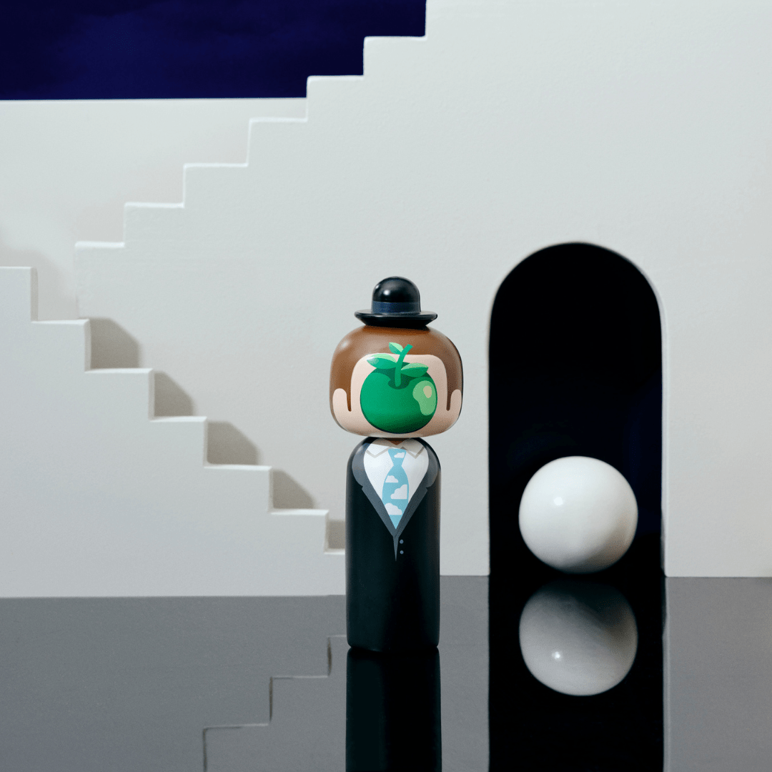 Une poupée kokeshi avec un visage en forme de pomme verte se tient devant un escalier et une arche blancs.