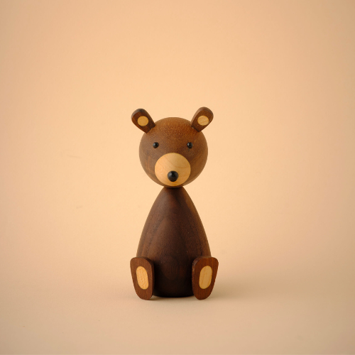 Figurine d'ours en bois au design simple et minimaliste sur fond neutre.