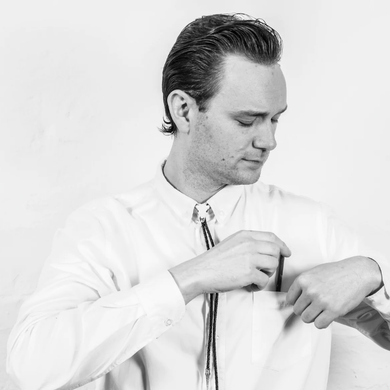 Une personne en chemise blanche plaçant un objet dans la poche de sa chemise.