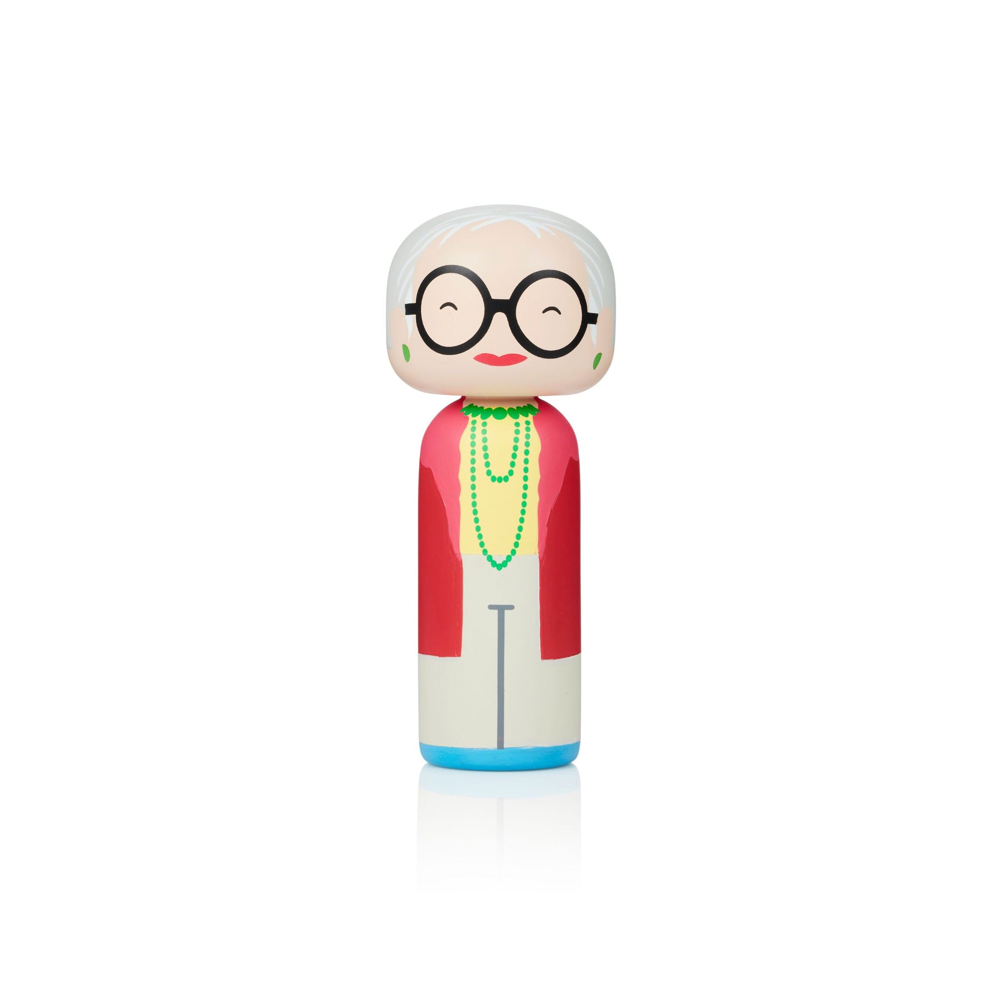 Une poupée kokeshi avec des lunettes, des cheveux blancs, une veste rouge, une chemise jaune et un collier vert sur un fond blanc.
