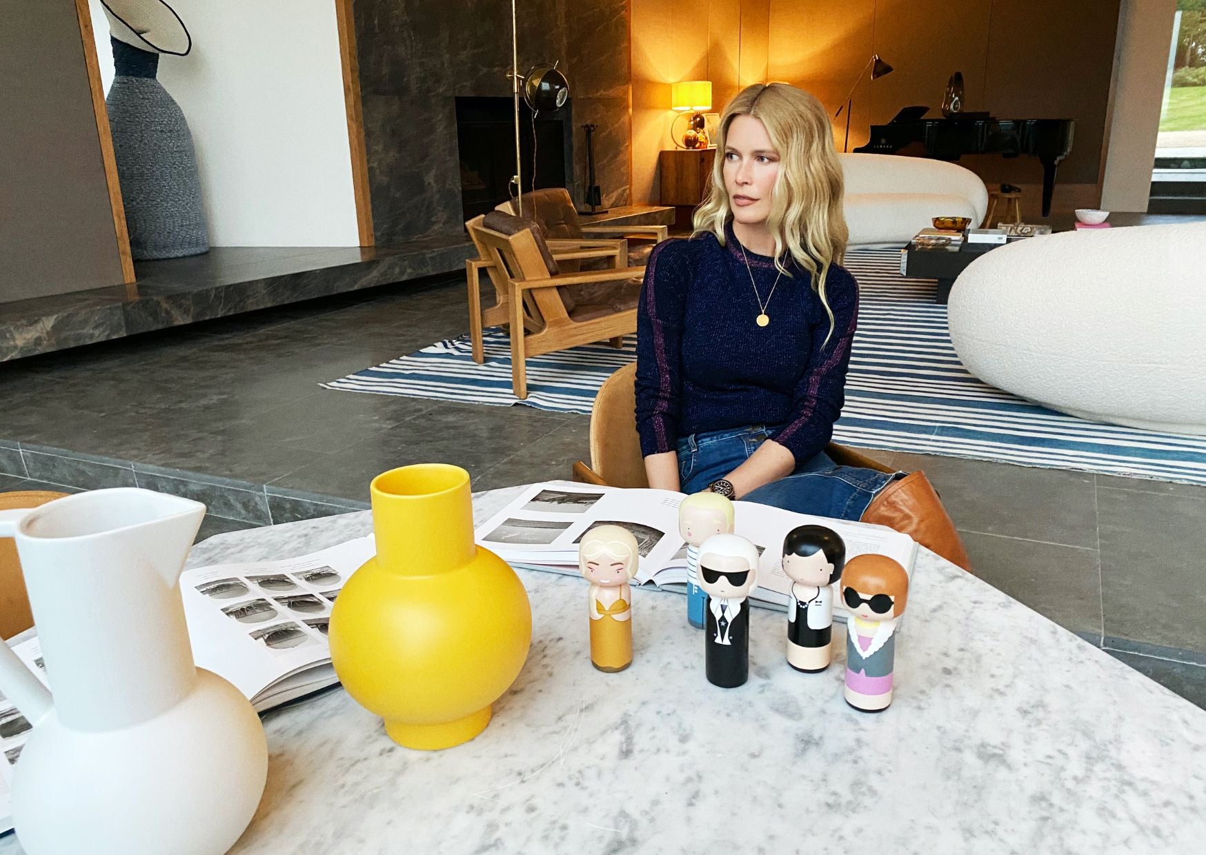 En kvinne sitter i en moderne stue med kokeshi-dukker og vaser på et marmorbord foran seg.