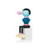 Colorful abstract wooden figure with a blue face, pink nose, and geometric body sitting on a white block.