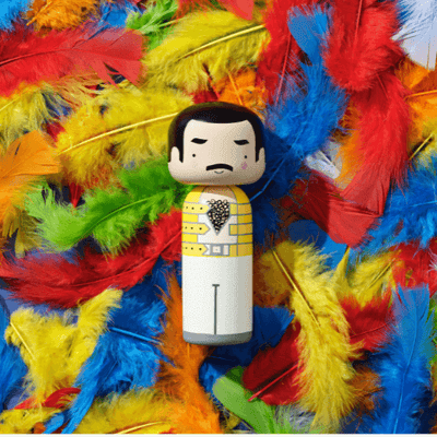 Kokeshi doll with a mustache on colorful feathers background.