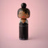 Lucie Kaas wooden kokeshi doll in elegant black evening gown with updo hairstyle on pink background