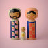 Lucie Kaas set of three pastel kokeshi dolls family with geometric patterns against pink backdrop