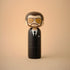 Lucie Kaas kokeshi doll in black suit with tie, brown hair, beard and yellow aviator glasses