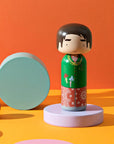Gio Lucie Kaas Kokeshi Doll from the Mira Mikati Collection in a Yellow setiing with pink and green decorations