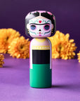 Frida, Dia De Los Muertos Kokeshi doll on purple background with yellow flowers