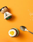 Eierhalter | Snufkin Freigeistiger EGG HOLDER auf gelbem Hintergrund mit einem weich gekochten Ei - Lucie Kaas