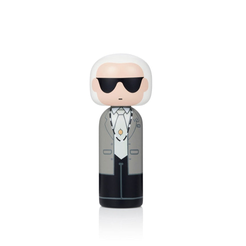 Une poupée kokeshi avec des cheveux blancs, des lunettes de soleil et un costume gris.